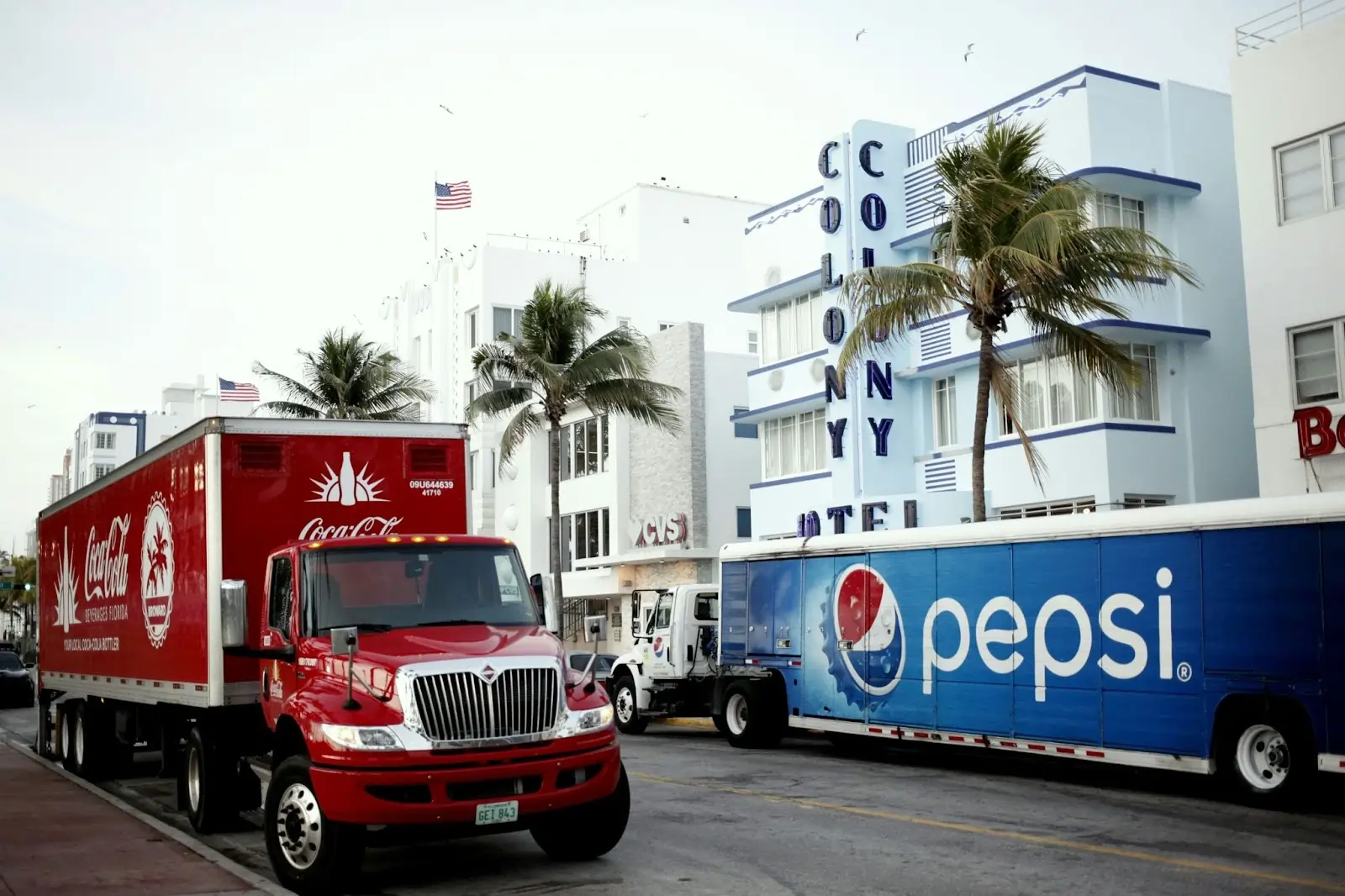 Caminhões da Coca e da Pepsi estacionados em lados opostos de uma rua.