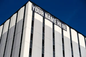Edifício visto de baixo com faixa no topo dizendo "Your Name Here" ("Seu Nome Aqui" em português)