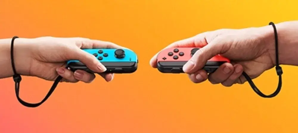 Duas mãos segurando um Nintendo Switch Joy das cores azul e vermelho.