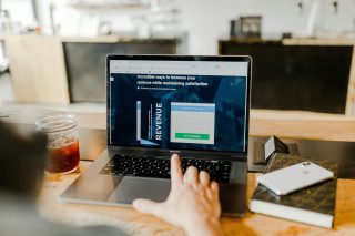 kpi Pessoa utilizando um laptop para visualizar um site sobre maneiras incríveis de aumentar a receita enquanto mantém a satisfação.